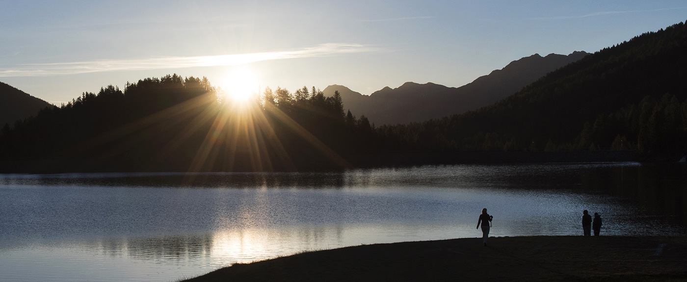 Escursionisti sulla sponda di un lago al tramonto